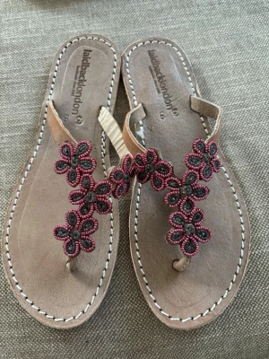 sandaler Laidback London s38 - Helt NYA! Snygga beige sandaler från Laidback London med handgjorda blommor i rosa och grå pärlor. Tårem och dekorativa sömmar runt sulan ger en bohemisk och unik look. Perfekta för sommaren och festivaler.