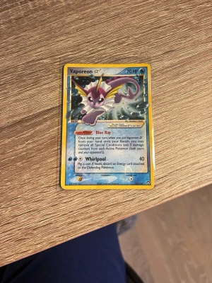 Vaporeon ☆ Pokémonkort - Säljer ett Vaporeon ☆ samlarkort från Pokémon TCG. Kortet har blå och gul ram, holografisk yta och motiv av Vaporeon. Text och detaljer på engelska. Perfekt för dig som samlar på Pokémonkort eller vill ha ett unikt tillskott till din samling.
