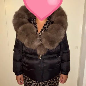 Svart pufferjacka med stor fuskpälskrage - Nu säljer jag en svart pufferjacka med stor, fluffig brun fuskpälskrage och bälte i midjan. Helt ny aldrig använt köpt men legat i garderoben 💕