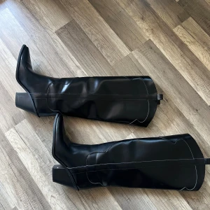 Svarta stövlar/boots - Snygga svarta stövlar i ”cowboy” modell. Bra modell om man har besvär med att stöveln inte gå över vaden. Blank svart färg, sparsamt använda ett par gånger. Perfekt till vardag och fest! Något små i storleken. Jag är vanligtvis 37/38. Dessa är i storlek 39. 