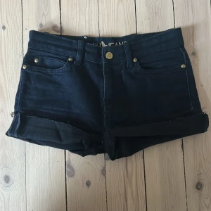 Mörkblå jeansshorts från MiH Jeans - Snygga mörkblå jeansshorts från MiH Jeans med klassisk femficksdesign, uppvikta benslut och guldiga detaljer. Shortsen har normal passform och är tillverkade i bomull med en liten broderad fågel på bakfickan. Perfekta för varma dagar eller för mysiga brunch dagar!🥂