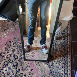 Mörkblå Replay anbass jeans med slitningar 31/34 - Säljer ett par mörkblå skinny jeans med slitningar och hål vid knäna. Jeansen har klassisk femficksdesign och smal passform hela vägen ner. Perfekta för dig som gillar en edgy och trendig look. Modellen är 178cm 70kg midja 37cm längd 101cm (22) lagning i skrevet