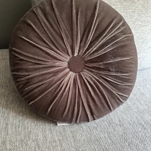 Kudde -  rund kudde i brun sammet med tvättlapp, material 100% polyester. Inga synliga defekter eller slitage. 