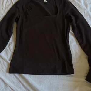 Svart långärmad topp från H&M - En svart långärmad topp från H&M i enkel och stilren design. Toppen har en fyrkantig ringning och är tillverkad i mjuk bomull, vilket gör den skön att bära. Perfekt att styla med jeans eller kjol för en clean look.