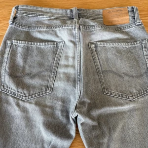 Grå jeans från Jack & Jones, 27/30 - Snygga grå jeans från Jack & Jones i klassisk femficksmodell. Jeansen har raka ben, normal passform och är tillverkade i bomullstyg med en lätt tvättad look. Perfekta för dig som gillar en stilren och avslappnad vibe.