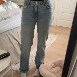 Mid wide ljusblå jeans, midja 25/30 - Säljer ett par ljusblå jeans med midwaist och wide fit. Klassisk femficksmodell med raka, vida ben och snygg tvätt. Jeansen är i bomull och har dragkedja och knapp framtill. Perfekta för en chill och trendig look. Defekt av en rispa på benet så priset är helt klart förhandlingsbart men de ser ut som en del av designen