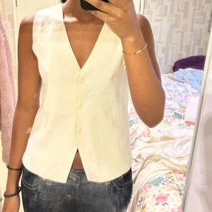 Vit väst - Snygg vit väst från Kappahl i storlek XS. V-ringad modell med tre knappar framtill och rak passform. Tillverkad i mjuk bomull, 