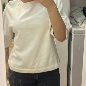 Vit basic tröja med halvkort ärm - Enkel och stilren vit tröja i mjuk bomull med halvkort ärm och rund halsringning. Kolla alla bilder då den har två fläckar. Ifrån Gina tricot 