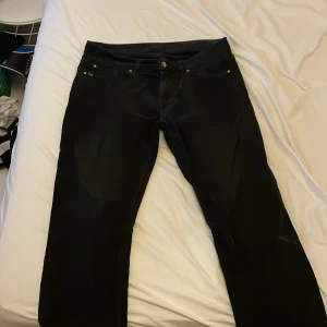 Svarta manchesterbyxor Tiger of Sweden - Svarta manchesterbyxor från Tiger of Sweden med klassisk femficksdesign och snygga detaljer. Byxorna har raka ben och diskret logga vid fickan. Perfekta för dig som gillar stilrena och tidlösa plagg med en modern touch.