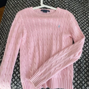  Ralph Lauren tröja - Supersöt ljusrosa kabelstickad tröja från Ralph Lauren med klassisk rund hals och broderad blå logga på bröstet. Tröjan är i 100% bomull och har långa ärmar samt ribbade muddar för en snygg passform. Storlek S. Skriv för mer bilder eller övriga frågor. 