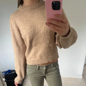 Beige stickad tröja med rund hals - Supermysig beige stickad tröja med rund hals och långa ärmar. Tröjan har en avslappnad passform och ribbade muddar vid ärmslut och nederkant. 