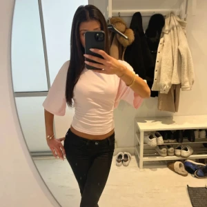 Ljusrosa omlottopp med knyt i ryggen - Supersöt ljusrosa topp med trekvartsärmar och snygg omlottdesign. Toppen har ett stort knyt i ryggen som ger en unik look och är croppad i modellen. Perfekt för dig som gillar trendiga och feminina plagg. Helt oanvänd med prislappkvar!💗