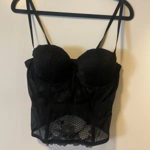 Supersnygg svart korsett - Jättefin svart korsett med spetsdetaljer och knäppe på baksidan. Super bra nu till halloween eller bara för en utekväll! I bra skick, säljer då den tyvärr inte passar mig längre. Står 40 på lappen men den är som en M i storleken. 