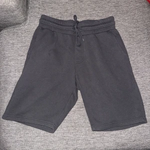 Svarta sweatshorts med snörning - Säljer ett par svarta sweatshorts med elastisk midja och snörning. Shortsen har två sidofickor fram och en bakficka. De är tillverkade i mjuk bomull och har en loose passform, perfekta för chill dagar eller träning.