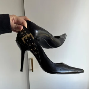Svarta pumps - Svarta spetsiga pumps med jättesnygga gulddetaljer som ett bälte. Storleken är 39 men lita på mig när jag säger att de är som en svensk 41/42. De är föör stora för mig som har 37-39 och min vän som har 40/41. Så dessa är för någon som har strl 41/42 skulle jag säga. Hade jättegärna velat behålla men de är alldeles för stora:/