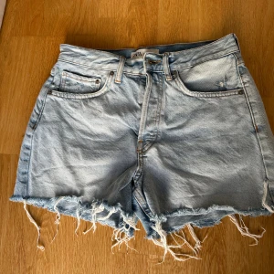 Ljusblå jeansshorts från Zara - Säljer ett par ljusblå jeansshorts från Zara med medelhög midja och fansiga kanter. Klassisk femficksmodell med knappgylf och bälteshällor. Perfekta för sommaren och ger en avslappnad vibe. Nypris: 359kr. Säljer för: 70kr!