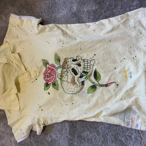 Gul Ed Hardy t-shirt med döskalle - Gul t-shirt från Ed Hardy med coolt tryck av döskalle och ros framtill. Den har en fläck på bilden men den förvann i tvätten, om du vill ha fler bilder är det bara att fråga! 💕