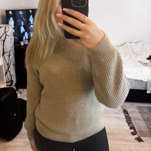 Beige stickad tröja med rund hals - Säljer en beige stickad tröja med rund hals och snygga ribbade detaljer. Tröjan har lång ärm och en klassisk, lite loose passform som är både chill och enkel att styla. Perfekt för dig som gillar neutrala färger och vill ha något mjukt och bekvämt.