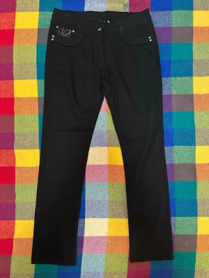 Svarta jeans med broderade detaljer - Svarta jeans med raka ben och snygga broderade detaljer samt små pärlor på fickorna både fram och bak. Klassisk femficksmodell med knapp och dragkedja i midjan. Perfekt för dig som gillar lite extra detaljer på dina byxor.