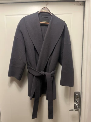 Mörkgrå kappa från Massimo Dutti - Snygg mörkgrå ullkappa från Massimo Dutti som var populär för några år sedan. Så snygg, passar perfekt för höst och vinter och lätt att matcha. Varsamt använd, jättefint skick, ej nopprig. Storlek small men är reglerbar med skräp så skulle säga att den passar XS-L. 😊Pris är diskuterbart. 