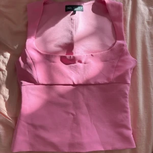 Rosa linnetopp från Zara - Snygg rosa linnetopp från Zara med breda axelband och fyrkantig urringning. Toppen är ärmlös och har en figurnära passform som ger en clean och modern look. Perfekt att styla med jeans eller kjol för en fräsch vibe. Toppen är i storlek L men den är otroligt liten i storleken så passar s/m. Säljer även en likadan i svart om man skulle va intresserad av den också💕