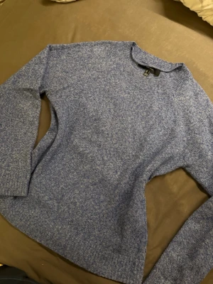 Blåmelerad stickad tröja Vero Moda - Mysig blåmelerad stickad tröja från Vero Moda i storlek S. Tröjan har rund halsringning, långa ärmar och ribbade muddar vid hals, ärmslut och nederkant. Perfekt för kyliga dagar och enkel att matcha med jeans eller kjol. Lite nopprig men annat i jättefint skick!