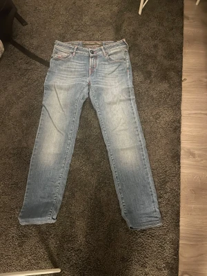 Ljusblå jeans från cohën - Säljer ett par ljusblå jeans från Jacob cohën med snygga röda detaljer på bakfickorna och klassisk femficksdesign. Jeansen har en rak passform och är tillverkade i mjukt denimtyg. Perfekt för dig som gillar en chill och stilren look.