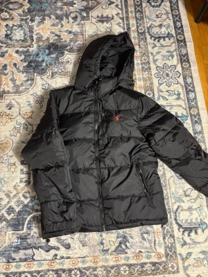 Svart pufferjacka från Polo Ralph Lauren - Polo Ralph Lauren jacka i nyskick. Använd få gånger och i mycket gott skick utan fläckar, hål eller slitage. Storlek S. Hög kvalitet och bekväm att bära. 