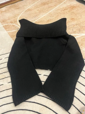 Svart croppad off shoulder tröja  - Snygg svart croppad off shoulder tröja och långa ärmar. Tröjan är stickad och har en modern, loose passform som passar perfekt till höst och vinter. Enkel att matcha med både jeans och kjol för en cool look.