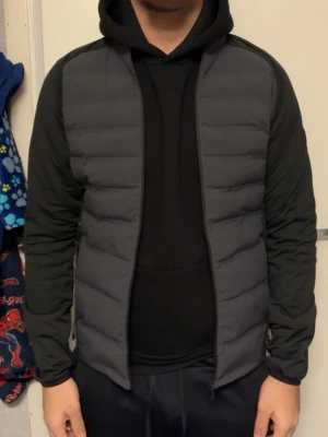 Svart pufferjacka från Sail Racing - Säljer en svart pufferjacka från Sail Racing med quiltad framsida och släta ärmar. Jackan har dragkedja framtill och en rund logotyp på ärmen. Perfekt för kyliga dagar och har en clean, sportig look.