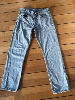 Ljusgrå raka jeans från Zara - Säljer ett par ljusgrå jeans från Zara i rak modell. Jeansen har klassisk femficksdesign, knappgylf och rå kant längst ner vid benslut. Materialet är jeans och färgen är ljusgrå, vilket ger en chill och clean vibe. Perfekt för dig som gillar enkel och stilren look. Liten fläck på ens bakfickan. 
