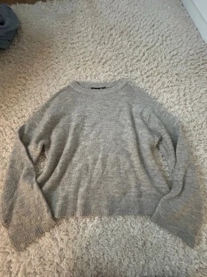Grå stickad tröja från 157 XS - Mysig grå stickad tröja från 157 i storlek XS. Tröjan har en klassisk rund halsringning och långa ärmar. Perfekt för att hålla sig varm under kyliga dagar och passar till jeans eller mjukisbyxor. Enkel och stilren design som funkar till många olika looks.