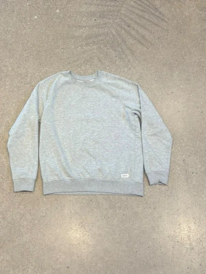 Ljusgrå sweatshirt från 157 Denim Makers - Säljer en ljusgrå sweatshirt från 157 Denim Makers i storlek M. Tröjan har rund hals, ribbade muddar vid ärmslut och nederkant samt en liten etikett framtill. Mjuk insida och klassisk passform, perfekt för chill dagar. Pris är diksuterbart!