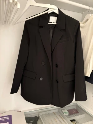Svart kavaj från NA-KD - En supersnygg kavaj från NA-KD i modellen ”Oversized Double Breasted Blazer” i storlek 34/xs. Prislappen är av med kavajen är helt oanvänd!