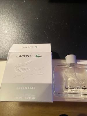 Lacoste Essential Eau de Toilette - Fräsch och stilren Eau de Toilette från Lacoste. Volymen är 125 ml, perfekt för dig som vill ha en klassisk och sportig parfym i din samling. Snygg flaska med Lacostes ikoniska krokodil på framsidan. Endast använt 4-5 sprut.