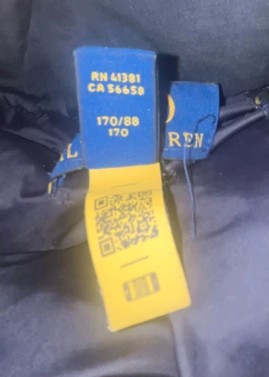 Svart pufferjacka från Polo Ralph Lauren - Säljer en svart pufferjacka från Polo Ralph Lauren med flera dragkedjeförsedda fickor och en liten röd logga på bröstet. Jackan har hög krage och huva, perfekt för kalla dagar. Klassisk och stilren design som funkar till det mesta.