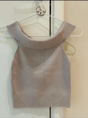  Ny Beige ärmlös topp - Säljer en stilren beige polotopp med bred krage och ärmlös design. Toppen har en rak och croppad passform som ger en modern look. Materialet känns mjukt och har en lätt struktur, perfekt för att matcha med jeans eller kjol.