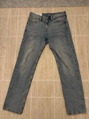 Ljusblå relaxed jeans från H&M - Säljer ett par ljusblå relaxed fit jeans från H&M. Modellen har klassisk femficksdesign, rak passform och normal midja. Jeansen är tillverkade i bomull och har en snygg tvättad look som ger en chill vibe. Jeansen har blivit använda ungefär 5 gånger och är i ett bra skick. Killen i bilden är 172 cm lång för referens.