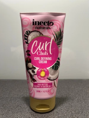 Inecto Curl Club Curl Defining Cream - Curl Club Curl Defining Cream från Inecto naturals är en rosa tub med guldigt lock, innehållande 200 ml kräm. Den är berikad med sheasmör, kokosolja och ricinolja, och är vegansk med 100% naturliga oljor. Perfekt för att framhäva lockar och minska friss.
