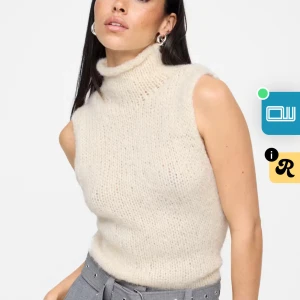 Stickad polotopp i ljus beige - Säljer en supermysig stickad polotopp i ljus beige. Toppen är ärmlös med hög krage och har en mjuk, fluffig känsla. Perfekt att styla med jeans eller kostymbyxor för en chill och trendig look. Materialet är stickat och ger en skön vibe.