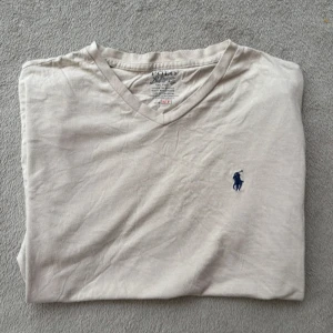 Ralph Lauren T-shirt  - Ralph Lauren T shirt i beige färg, väll använd, finns kanske något tecken på att den är använd men inget man tänker på. Size S men passar Medium