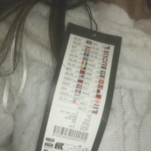 Vit offshoulder stickad tröja - Superfin vit stickad tröja med bred offshoulder-ringning och kabelstickat mönster. Tröjan har långa ärmar och en loose fit som ger en chill och trendig vibe. Perfekt att styla med jeans eller kjol för en snygg look.