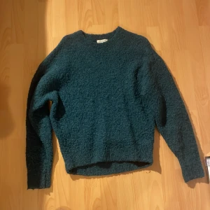 Mörkgrön stickad tröja - Mysig mörkgrön stickad tröja från & Other Stories, Stockholm Atelier. Material Alpacka 22%. Perfekt för att hålla värmen under kyliga dagar och passar dig som gillar en enkel men cool look.