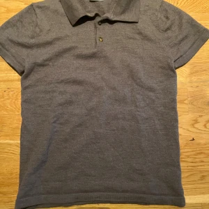 Grå pikétröja från John Henric - Snygg grå pikétröja från John Henric i storlek S. Klassisk krage och två knappar framtill. Mjuk och skön känsla, perfekt för dig som gillar stilrena och enkla plagg. Passar dig som vill ha en basic piké med clean look. Men den har tyvärr krympt.