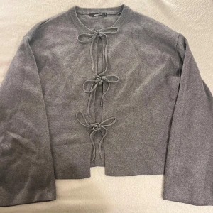 Grå kofta med knyt från Gina Tricot - Grå kofta från ginatricot som man kan knyta. Perfekt för kylan. Bilderna visar små defekter på koftan  vilket påverkar priset, men de syns inte när man har på sig koftan och har knutit den. 😊