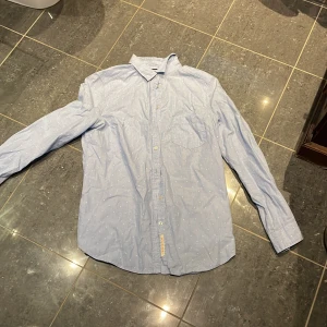 Blå prickig skjorta Holly & Whyte - Snygg ljusblå skjorta från Holly & Whyte med vita prickar och tunna ränder. Klassisk krage, bröstficka och knappar framtill. Långärmad och tillverkad i mjuk bomull, perfekt för dig som gillar stilrena detaljer.