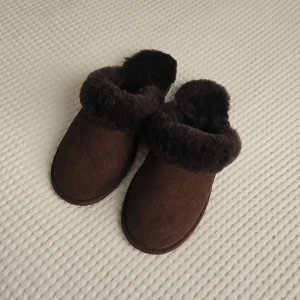 Bruna fårskinnstofflor från Hemtex storlek 39-40 - Mysiga bruna tofflor från Hemtex i äkta lammull med fluffig kant och mjuk insida. Yttermaterialet är mocka och sulan är i EVA för extra komfort. Perfekta att glida runt i hemma när det är kallt ute. Nypris 800 kr