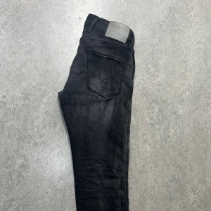 Svarta Replay Anbass jeans skinny fit - Säljer ett par svarta Replay Anbass jeans. Jeansen har en cool design med lite gråa linjer här och där. Riktigt feta jeans🔥köpt för 1200kr. 
