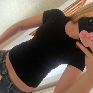 Svart tight kortärmad T-shirt - En svart, tight och basic T-shirt/topp med korta ärmar och rund halsringning. Sitter figurnära. 