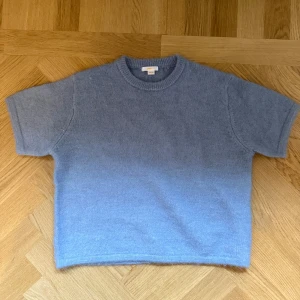 Blå stickad tröja från Gina Tricot - Mysig blå stickad tröja från Gina Tricot i storlek 158/164. Tröjan har korta ärmar och rund halsringning. Använd 1 gång.